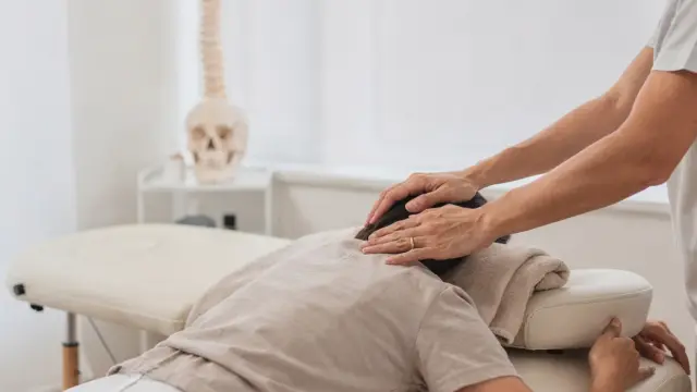 Osteopathie bei Kopfschmerzen: Behandlungstisch mit Anatomiemodell von Schädel und Wirbelsäule