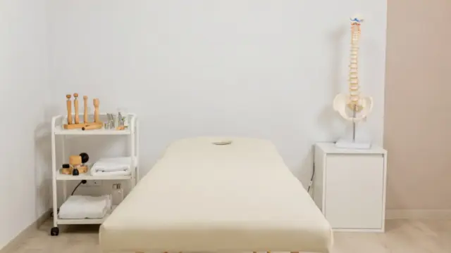 Osteopathie-Behandlungsraum mit Behandlungsliege und Wirbelsäulenmodell zum Thema wissenschaftliche Anerkennung