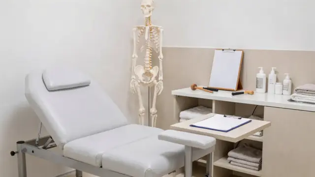 Osteopathie im Ausland: Behandlungsraum mit Liege, Anatomiemodell und Unterlagen