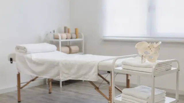 Osteopathie bei Beckenproblemen nach der Geburt in einer hellen Praxis mit Beckenmodell und Behandlungsliege