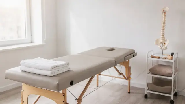 Osteopathie-Behandlungsraum mit Behandlungsliege und Wirbelsäulenmodell zum Thema Was macht ein Osteopath?