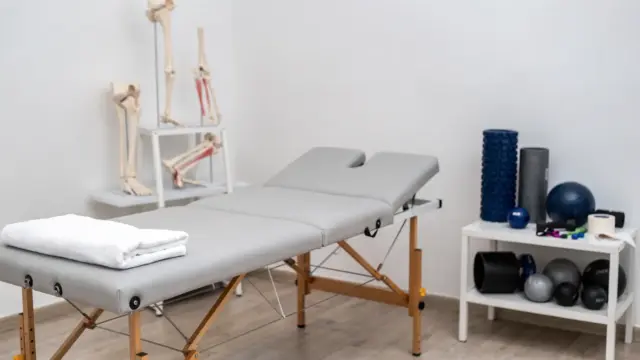 Osteopathie bei Sportverletzungen: Behandlungsraum mit Therapieliege, Anatomiemodell und Tapes