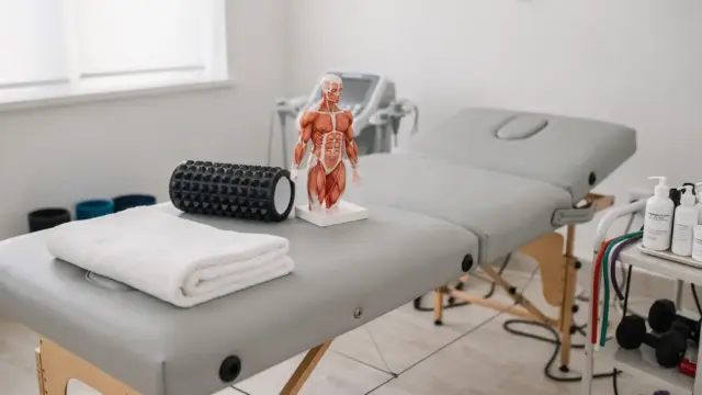 Osteopathie bei Muskelverspannungen: Behandlungsliege mit Anatomiemodell und Therapie-Zubehör