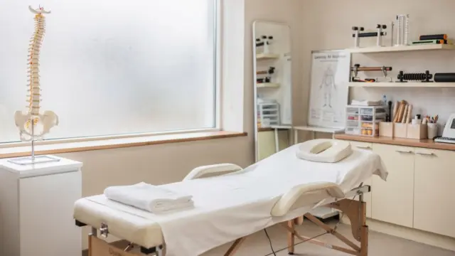 Osteopathie-Behandlungserfolg erkennen: ruhiger Behandlungsraum mit Behandlungsliege und Wirbelsäulenmodell