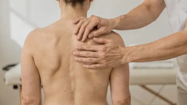 Osteopathie bei Husten: Hände behandeln den oberen Rücken in einer hellen Praxis