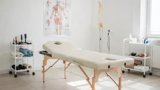 Osteopathie bei Rückenschmerzen: Behandlungsraum mit Liege und Wirbelsäulenmodell