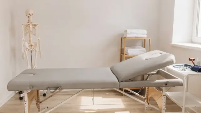 Leerer Behandlungsraum mit Liege und Anatomiemodell zum Thema Osteopathie-Warnzeichen